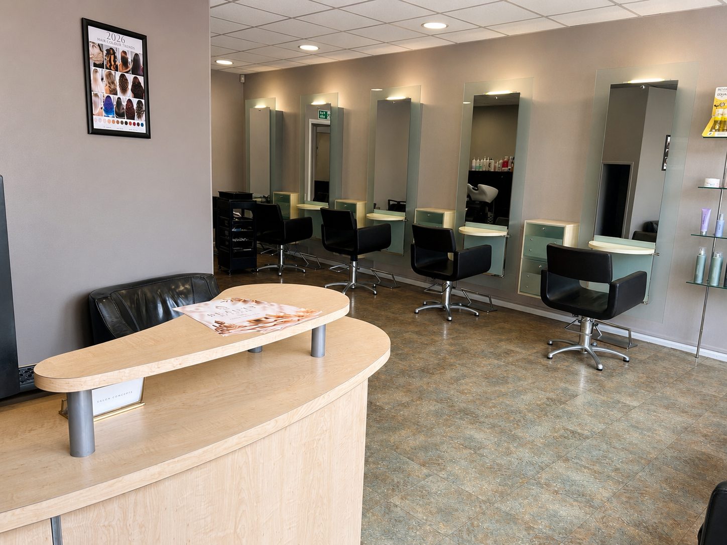 The salon reception desk and styling chairs, lit by mirror lights