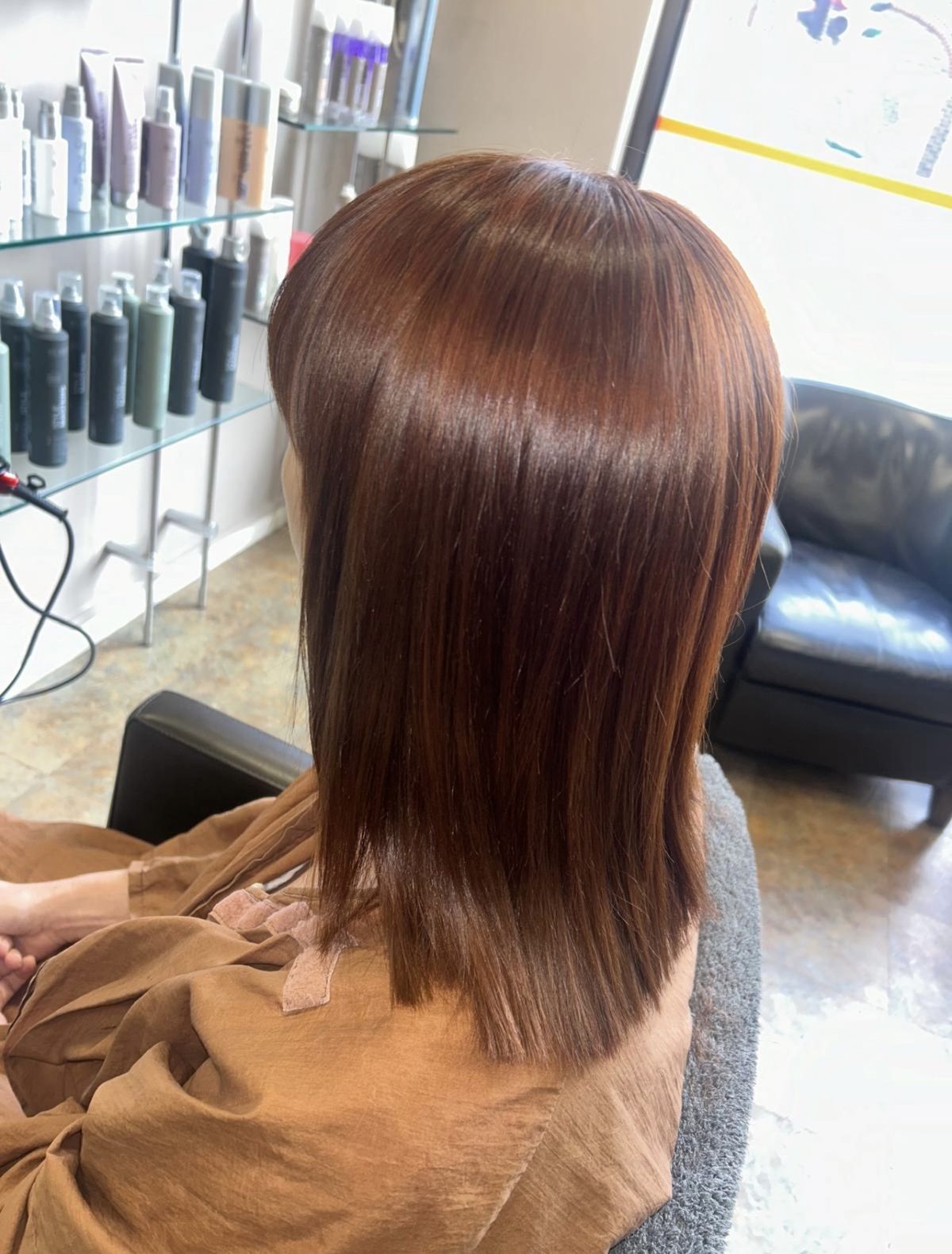 Glossy copper-brown hair cut to a sleek shoulder-length shape